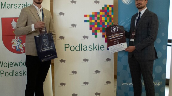 Uczestnicy konferencji pozują do zdjęcia przy banerze Województwa Podlaskiego